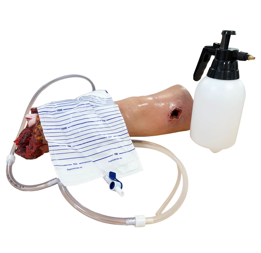 A simulated traumatic arm training model connected to tubing and a fluid bag beside a white spray bottle.